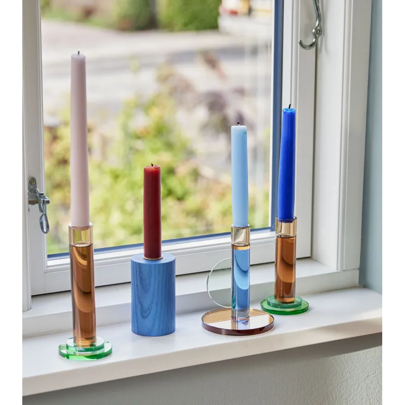 Ensemble de bougeoirs colorés sur un rebord de fenêtre.
