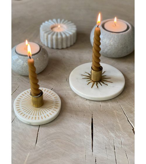 Composition de bougeoirs en marbre et chandelles allumées, ambiance chaleureuse.