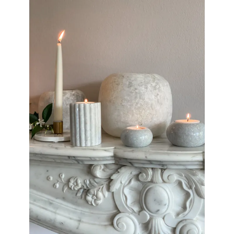 Bougeoir en marbre L placé sur une cheminée en marbre, entouré de bougies et d’éléments naturels pour une ambiance douce.