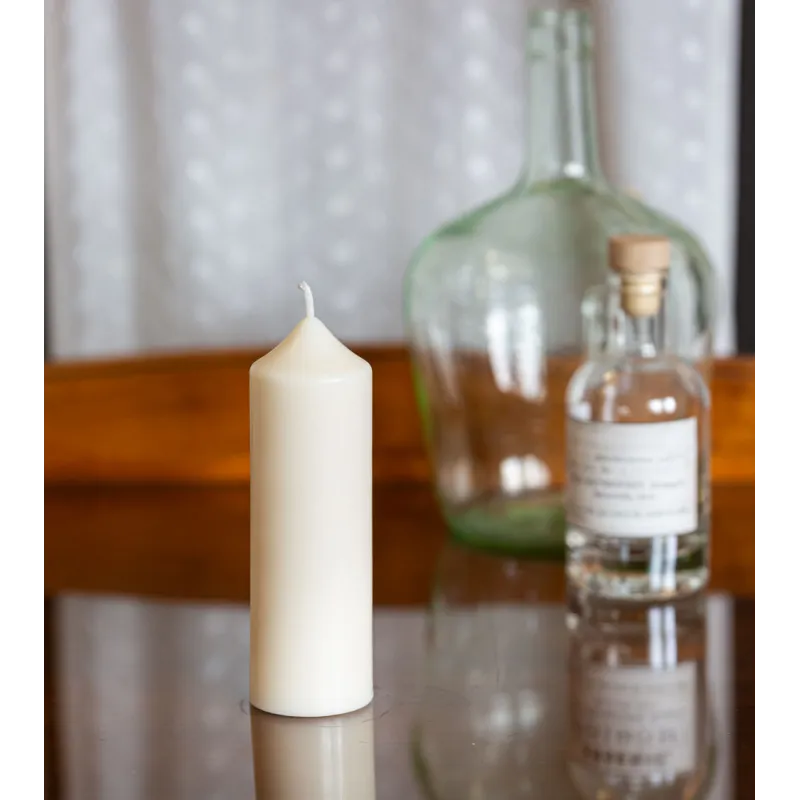 Bougie artisanale en cire naturelle de colza Ø 5 cm H 14 cm posée sur une table en verre