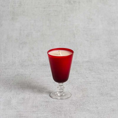 Bougie parfumée dans un verre à pied rouge élégant.