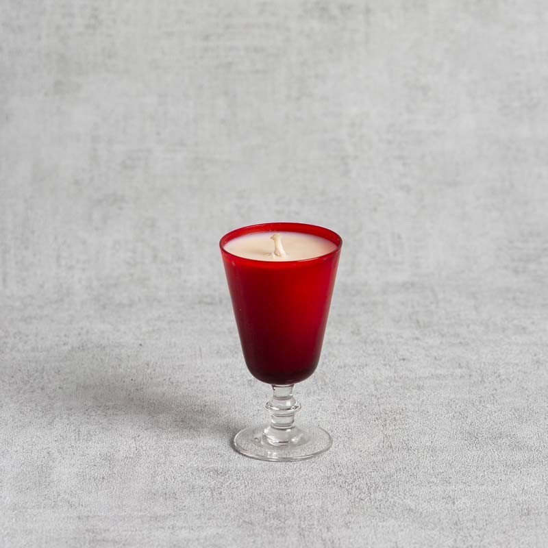 Bougie parfumée dans un verre à pied rouge élégant.