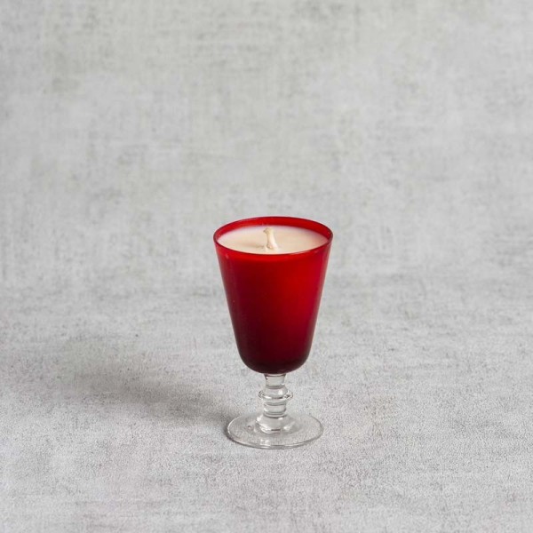 Bougie parfumée dans un verre à pied rouge élégant.